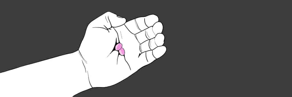 Hand holding two pink abortion pills